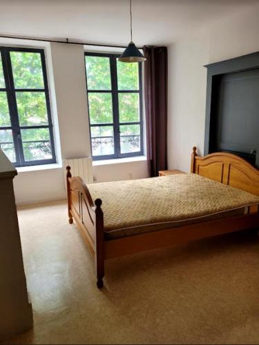 - une chambre avec un lit en bois et 2 fenêtres dans l'établissement A DEUX MINUTES DU CHATEAU FORT de SEDAN, à Sedan