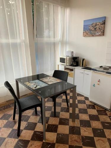 une cuisine avec une table en verre et deux chaises dans l'établissement Vacances à 50m de la plage et de la mer, à Trégastel