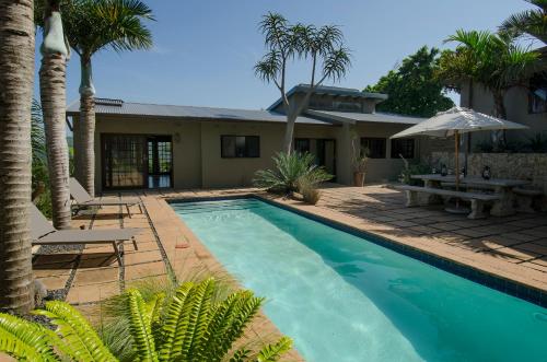a swimming pool in front of a house with palm trees at Villa La Mercy Guest Suite, No load shedding or water outages in La Mercy