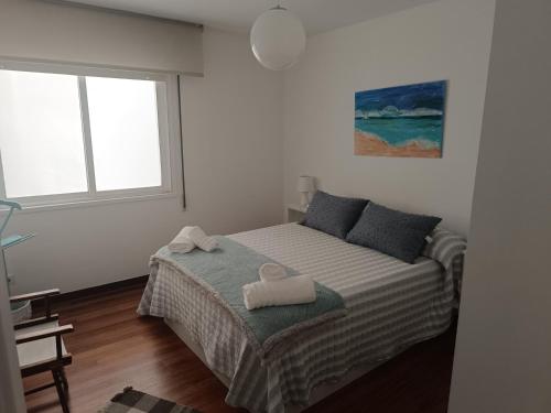 a bedroom with a bed with two towels on it at Vistas al Puerto in Pobra do Caramiñal