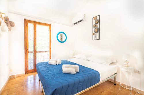 a white bedroom with a blue bed with towels on it at Villetta degli Oleandri - Geremeas 2 in Geremeas