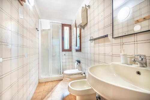 a white bathroom with a sink and a toilet at Villetta degli Oleandri - Geremeas 2 in Geremeas