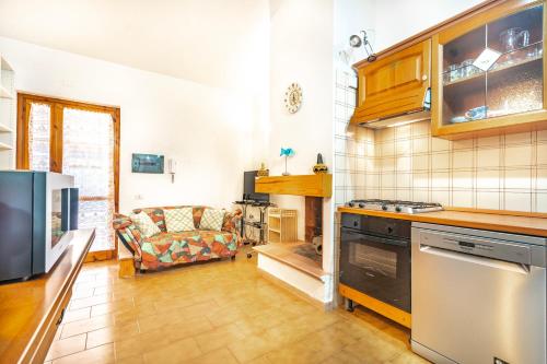 a kitchen with a stove and a couch in a room at Villetta degli Oleandri - Geremeas 2 in Geremeas
