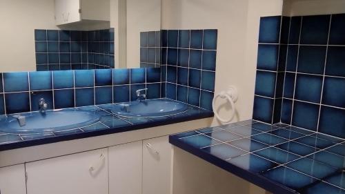 La salle de bains est pourvue de 2 lavabos et de murs carrelés bleus. dans l'établissement Appartement 3P Centre Bourg La Reine face à la Gare REB B - Paris à 10mn, à Bourg-la-Reine