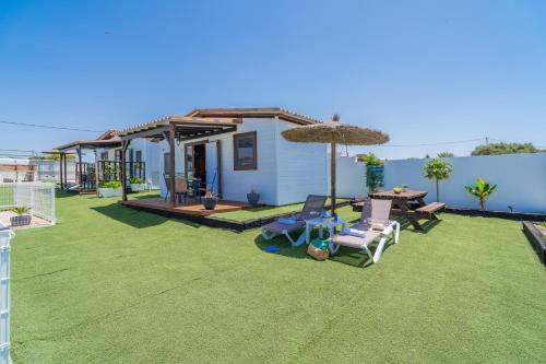 a yard with chairs and an umbrella and a house at El Paraíso Perdido in Conil de la Frontera