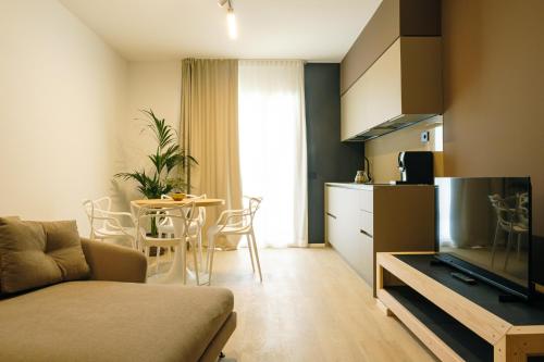 a living room with a couch and a kitchen with a table at Camoma Aparthotel - Suites Apartments in Jesolo