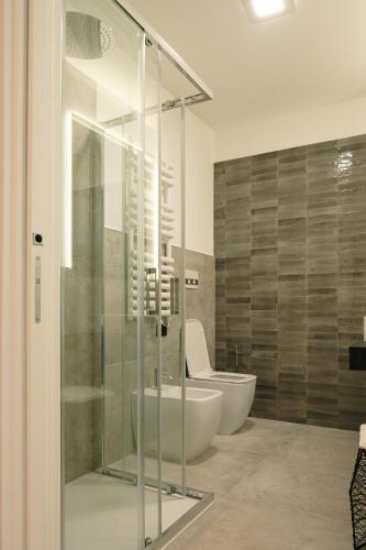a bathroom with a glass shower and a toilet at Camoma Aparthotel - Suites Apartments in Jesolo