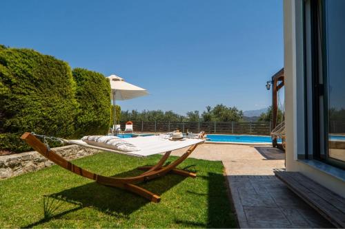 a table and chair on the grass next to a pool at Villa Nimertis in Xirokámbion
