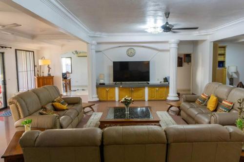 a living room with couches and a flat screen tv at Sound of the Sea Villa PD in Port Dickson