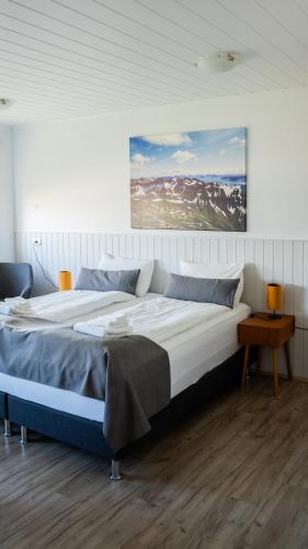 a large bed in a bedroom with a painting on the wall at Hótel Flókalundur in Brjánslækur