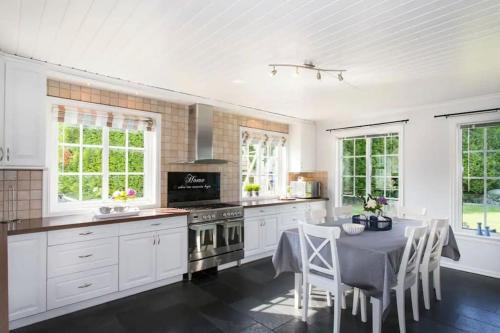a kitchen with white cabinets and a table with chairs at Spectacular nature experience at Norway's southern point! in Svenevik