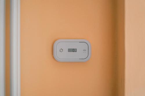 a thermostat on an orange wall next to a door at Le Ortensie in Paesana