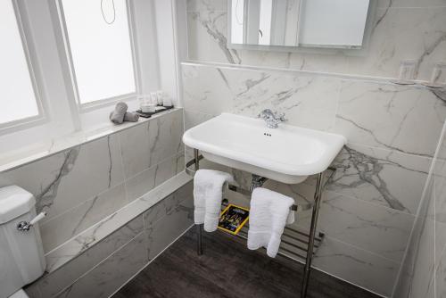 a white sink in a bathroom with marble walls at Horsted Place Hotel in Uckfield