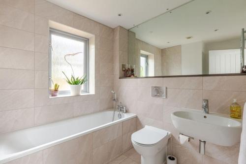 a bathroom with a tub and a sink and a toilet at Modern City Centre House with Free Parking in Canterbury