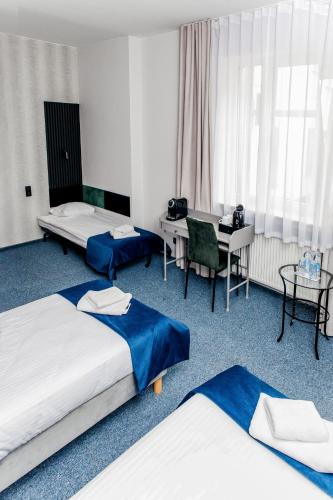 a hotel room with three beds and a desk at Elegant Apartments in Poznań