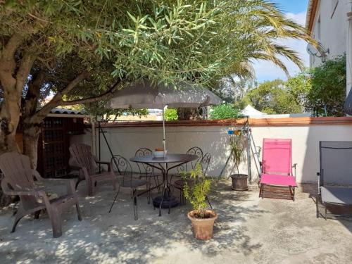 un patio avec une table, des chaises et un parasol dans l'établissement Charmant appartement de vacances, à Argelès-sur-Mer