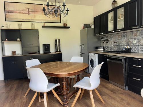 - une cuisine avec une table en bois et des chaises blanches dans l'établissement Maison de ville 5 min de la gare, à Bordeaux