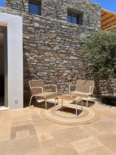 two chairs and a table in front of a stone wall at Egeo Paros in Kampos Paros