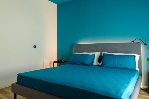 a blue bedroom with a bed with a blue wall at Camoma Aparthotel - Suites Apartments in Jesolo