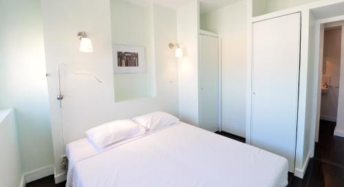 um quarto branco com uma cama e um espelho em Appart' Belvedere em Lyon
