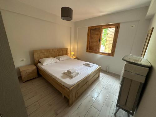 a bedroom with a bed with white sheets and a window at Dhermi Village Apartments in Dhërmi
