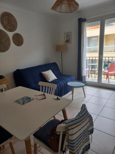 un salon avec un canapé bleu et une table dans l'établissement CANET Plage appartement vue latérale mer, 1 chambre , WIFI, climatisation, parking sécurisé couvert, à Canet