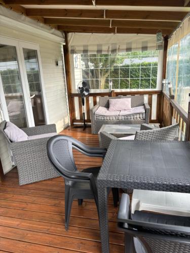 - une terrasse couverte avec des chaises et des tables en osier dans l'établissement Mobilhome cosy 520, à Saint-Arnoult