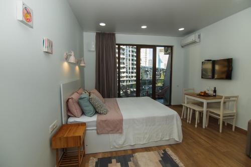 a bedroom with a bed and a table and a balcony at Double room in Next Orange in Batumi