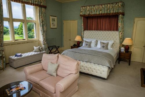 a bedroom with a bed and a couch and a chair at Horsted Place Hotel in Uckfield
