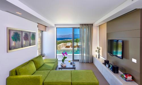 a living room with a green couch and a large window at Youphoria Sea View Villas in Kissamos