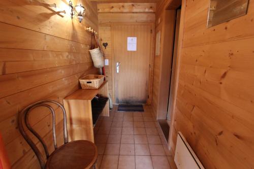 a hallway in a cabin with a chair and a table at Le Gros Pâquier in La Lécherette