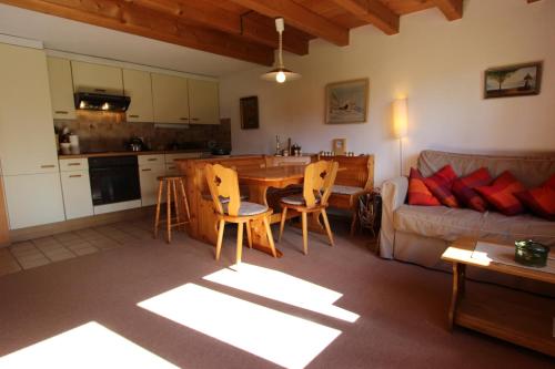 a kitchen and living room with a couch and a table at Le Gros Pâquier in La Lécherette