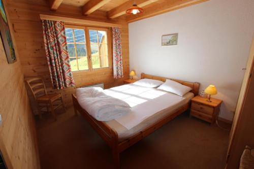 een slaapkamer met een groot bed in een houten huis bij Le Gros Pâquier in La Lécherette