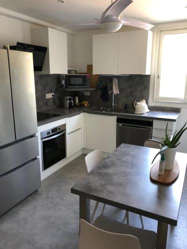 une cuisine avec une table et des chaises et une cuisine avec des appareils blancs dans l'établissement Chambre avec salle d'eau privée dans appartement partagé 200 m du tram, à Montpellier
