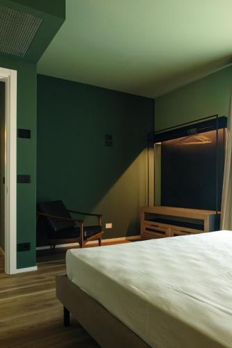a green bedroom with a bed and a chair at Camoma Aparthotel - Suites Apartments in Jesolo