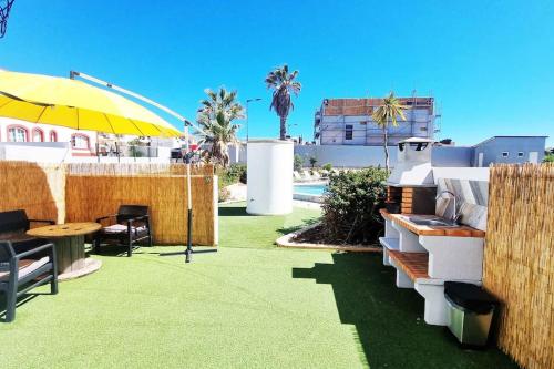 a patio with a table and a yellow umbrella at Sun & Fun in Sagres in Sagres