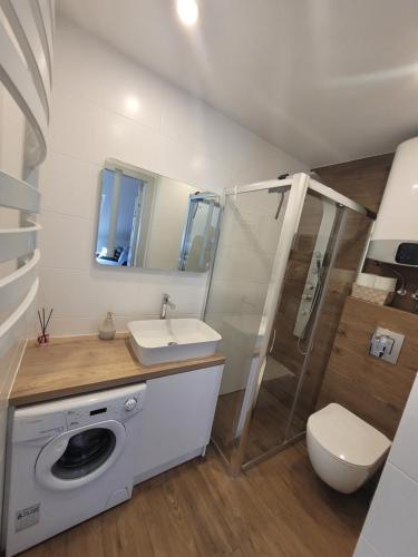 a bathroom with a sink and a washing machine at Apartamenty Platinum 2 in Łukęcin