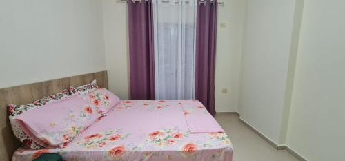 a bedroom with a pink bed with pillows and a window at View Saranda Center in Sarandë