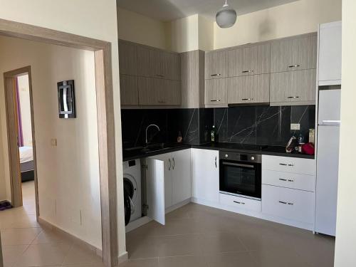 a kitchen with white cabinets and a washer and dryer at View Saranda Center in Sarandë
