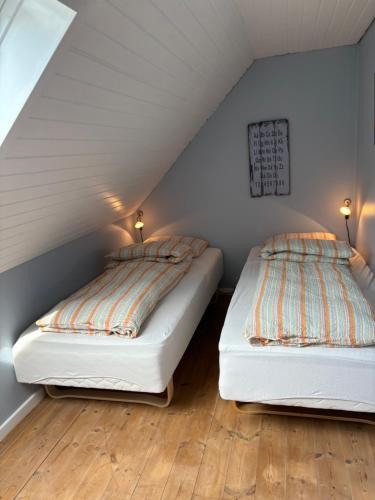 two beds in a room with white walls and wood floors at Feriehus Vrensted-Løkken in Løkken