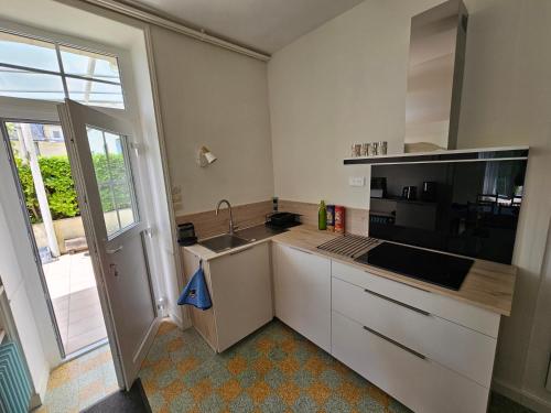 a kitchen with white cabinets and a sink and a window at La Maison du Bourg Joly in Bourgueil