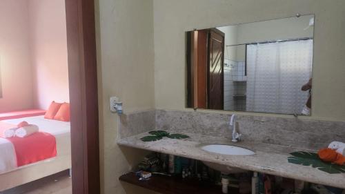 Un baño con lavabo, espejo y cama. en Vila Feliz Arraial, en Arraial d'Ajuda