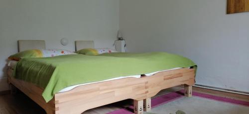 a bedroom with a wooden bed with a green blanket at Rita's FeWo in Grossschönau