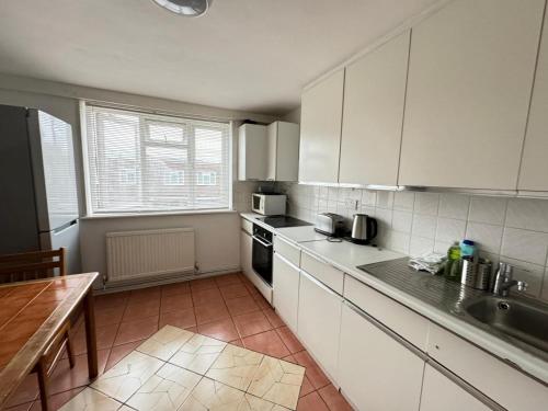 a kitchen with white cabinets and a table in it at PRP Pennack Road Peckham London in London