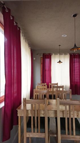 a dining room with red curtains and a table and chairs at Tsogstot residency in Deskit