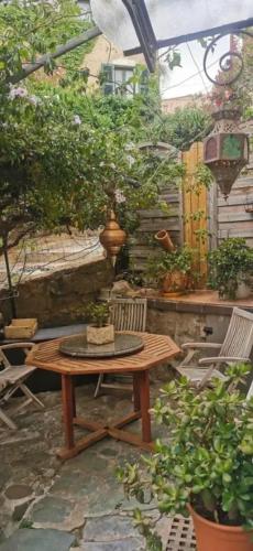 a patio with a wooden table and chairs and plants at Maison charmante à Monticello avec jardin privé in Monticello