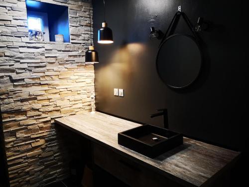 une salle de bain avec un lavabo et un mur en pierre dans l'établissement GITE BRETON sur la côte de granit rose, à Pleudaniel