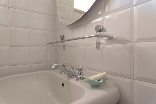 a white bathroom with a sink and a mirror at Argentario Retreat Sea View Terrace, WiFi & Private Parking Included in Porto Santo Stefano
