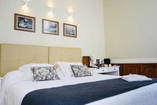 a bedroom with a large white bed with two pillows at Casa Rosa Hotel Boutique in Petrópolis