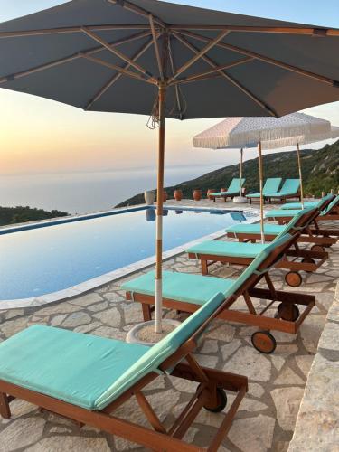 a row of lounge chairs and an umbrella on a pool at Sun Castle Houses in Drymon